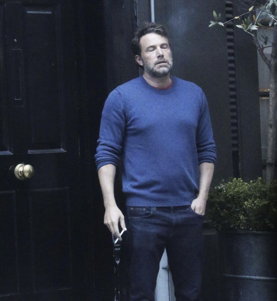 Ben Affleck smoking a cigarette while looking depressed and frustrated.