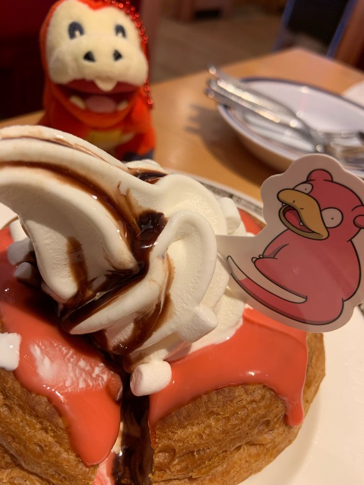 ピンクが鮮やかなコメダのヤドンシロノワールの奥からホゲちゃんぬいがこっちを見ている