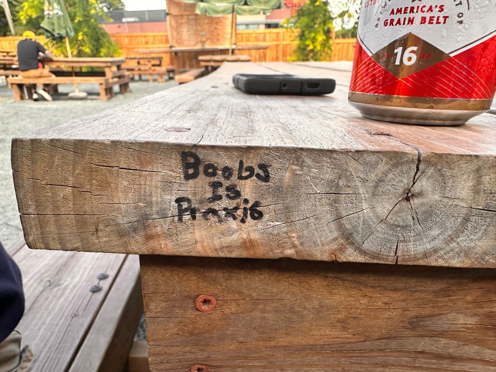 Graffiti on a table that reads boobs is praxis