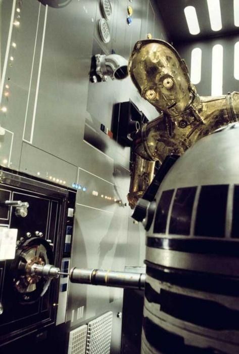 C-3PO looking at R2-D2 plugged into a starship computer.