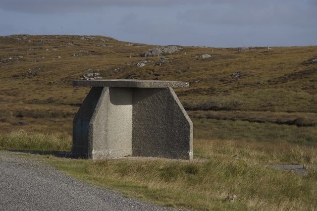 A bus shelter in Lewis. A concrete four walled cross structure, topped by a concrete capstone