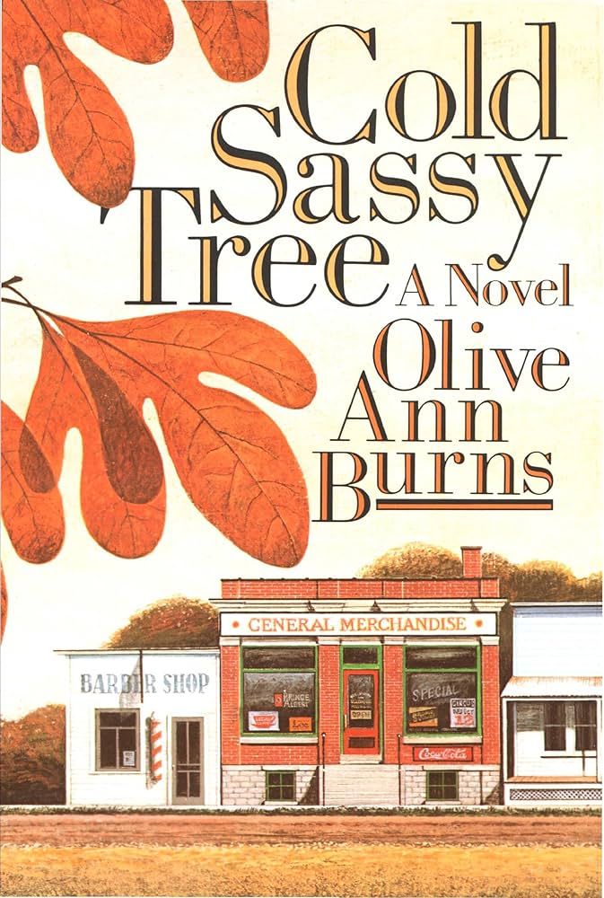 Book cover for Cold Sassy Tree a novel by Olive Ann Burns. Image depicts a small town General Merchandise store next to a barber shop and another non-descript building sitting on a dirt road. There are several leaves on the left side and trees behind the buildings. Done in warm tones of red, orange, yellow, and tan.