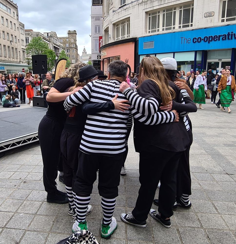 Huddle of locking dancers - funky femmes - in Liverpool city getting ready to perform to a waiting crowd. They are dressed in black and white stripes and not all are women