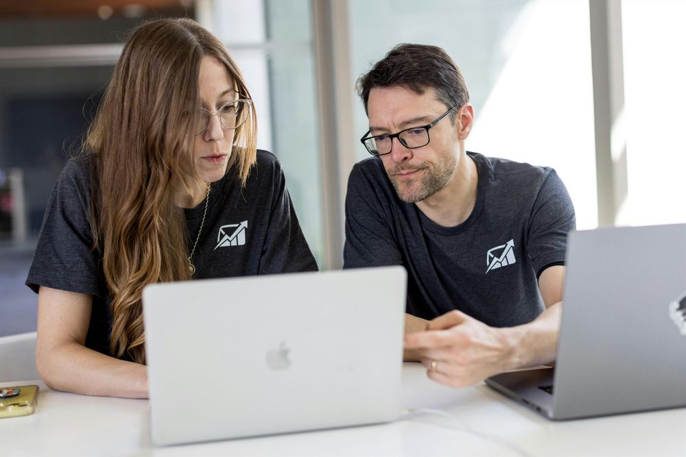 Two people in an office looking at a laptop