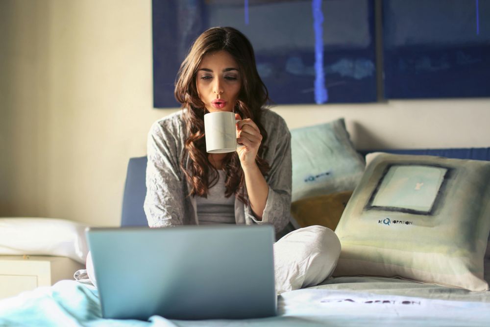 Woman drinking tea and looking at a laptop