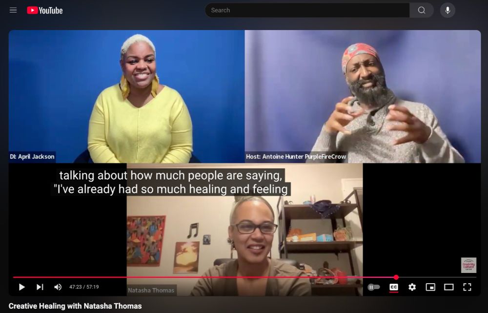 A screenshot from the DCC’s YouTube video “Creative Healing with Natasha Thomas” shows three participants in a Zoom meeting. In the top left corner is Deaf interpreter April Jackson, smiling and wearing a bright yellow sweater with matching yellow feather earrings. In the top right is moderator Antoine Hunter (PurpleFireCrow), an African Indigenous person with locs and a full beard, signing. Below them is speaker Natasha Thomas, a brown-skinned person with short, graying hair, smiling. The video captions read: “...talking about how much people are saying, ‘I’ve already had so much healing and feeling…’” The Youtube logo and search bar is at the top and the DCC logo is at the bottom.