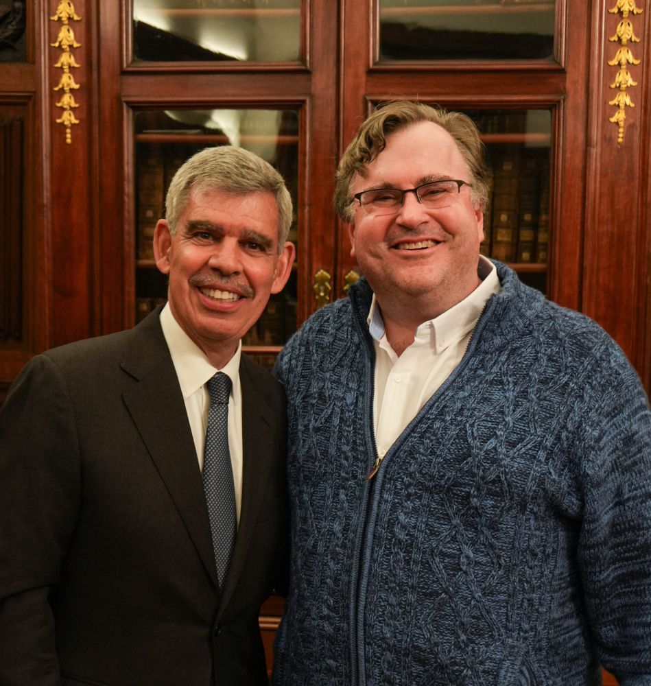 Reid Hoffman stands beside Dr Mohamed El-Erian, both wearing smart outfits.