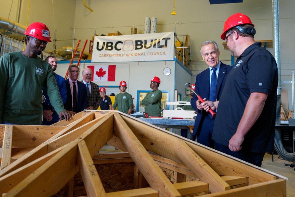 Mark Carney helping to build something with carpenters. 