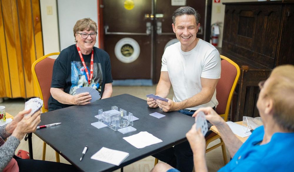 Pierre Poilievre playing cards with people in Todfield, Alberta.  