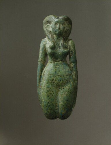 Faience figurine of a dancing-girl. Turquoise blue glaze with details (hair, eyes, and eyebrows, ornaments) in purplish black. The figure is rather well-modeled, with slender waist and swelling thighs. The upper arms are free from the body, but hands and lower arms lie close to the thighs. The legs end (as is frequent in servant-figurines of the period) in rounded stumps at the knees. The girl wears a “Hathor” wig with spiral curls in front and straight, squared lock in back, and is nude save for a girdle of cowrie-shells and beads and bead necklaces, indicated by black markings. Black dots arranged in lozenges on legs probably indicate tattooing. The pubic triangle is emphasized by black dots.
Condition: Broken through the middle and repaired. Black spots worn in places. Brownish traces of (?) clay mould. Otherwise perfect. 
