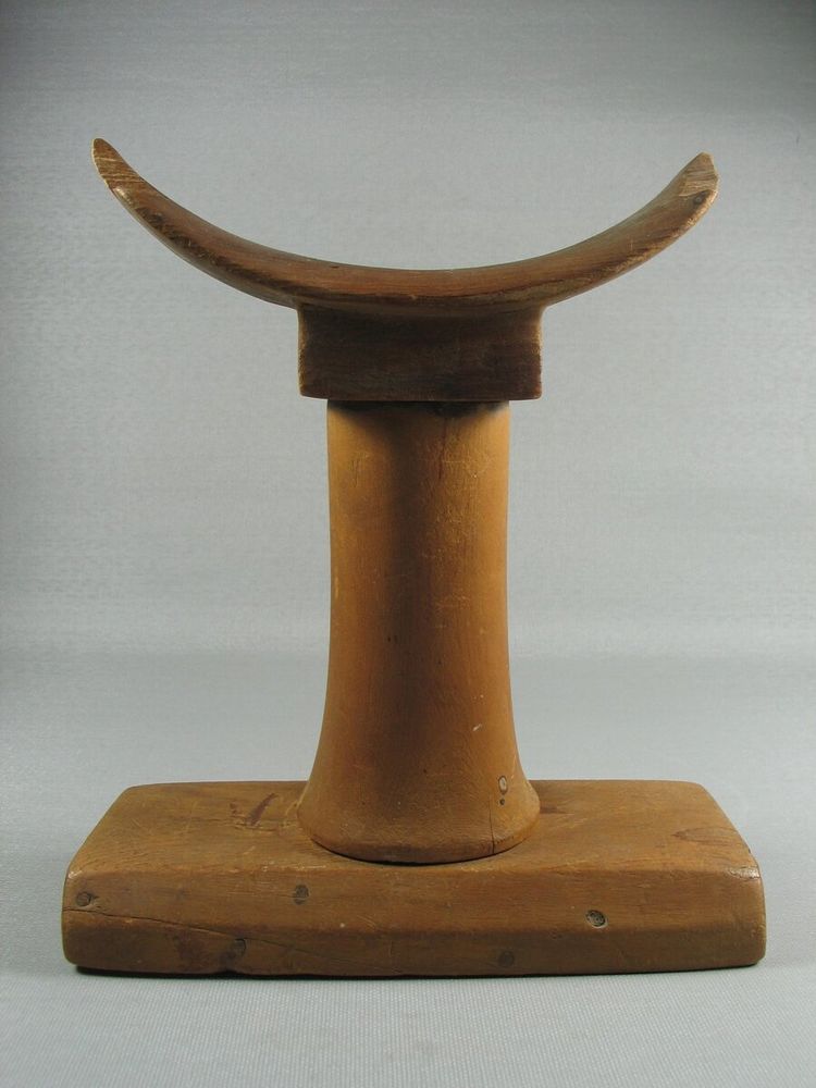 Undecorated wooden headrest of conventional form. Possibly a provincial piece. 
Condition: Each end of curved portion of headrest badly chipped, otherwise good. Top of headrest appears ancient, cylindrical support and base look dubious. Possibly an assembled piece, although at present it is impossible to say that the piece is a forgery. Base seems small for support and the beveled edge is hard to explain.