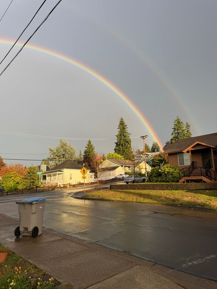 one half of a double rainbow in a suburban neighborhood 