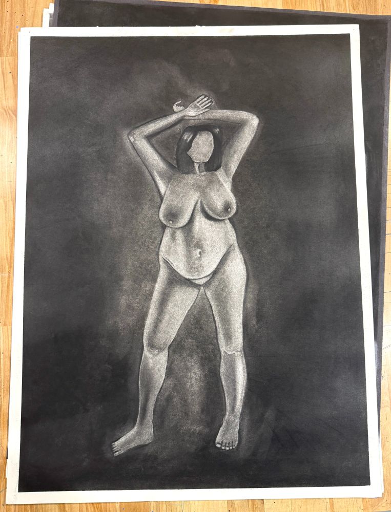 A figure drawing of a female nude body. This piece is utilizing the reductive method of drawing, where the paper is covered in a layer of charcoal and then I take an eraser to create the female figure. 