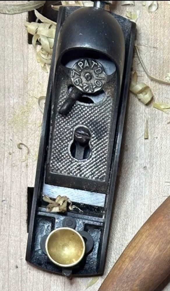 A close up of an old photo of the block plane showing the dark bare iron of the old lever cap 