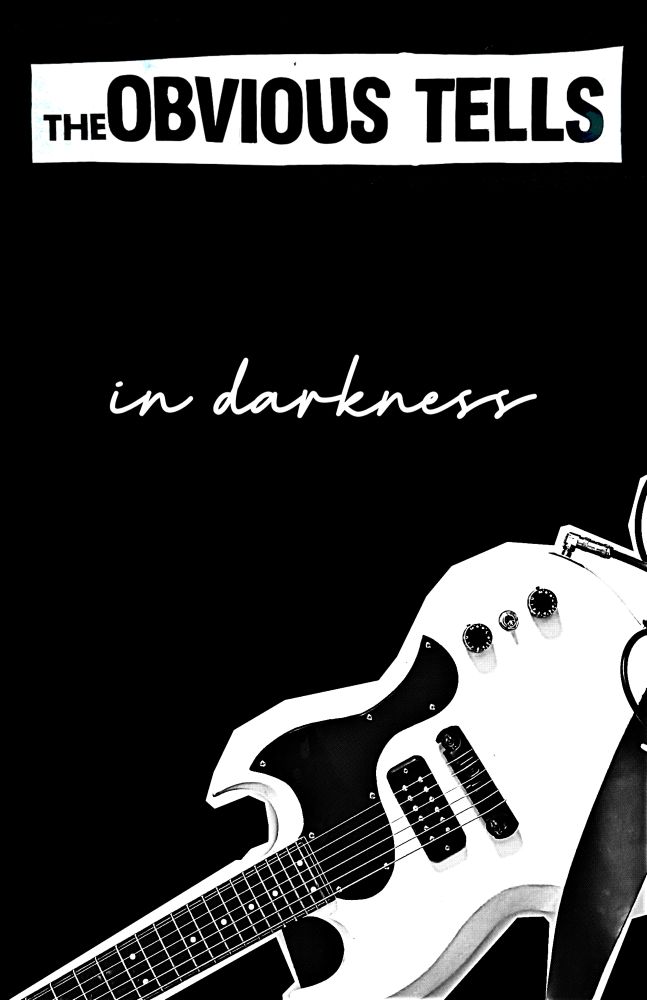 A picture of a guitar below the obvious tells logo and the cursive words “in darkness”, all done up zine style 