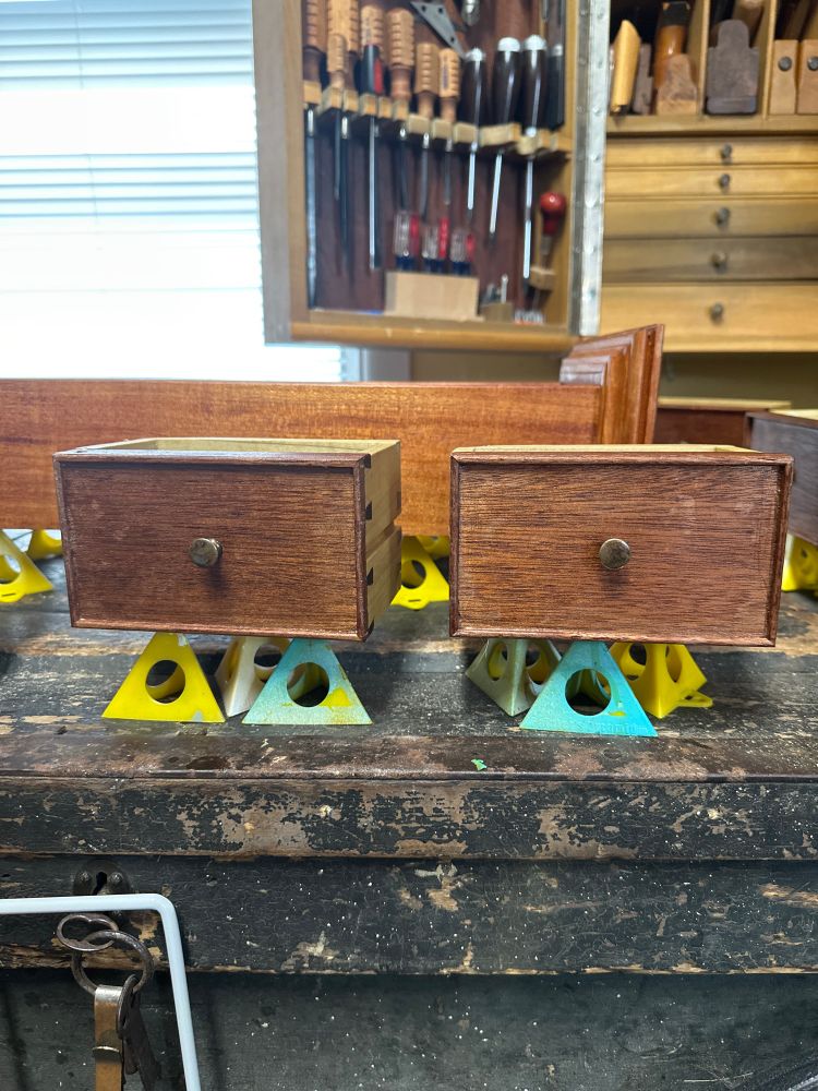 A closeup of two tiny drawers sitting on painters pyramids on the worn tool chest  
