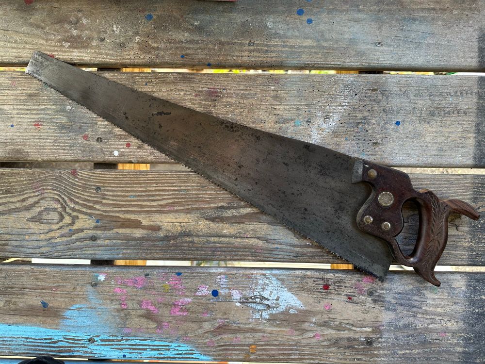 A wide shot of the saw on the porch. It has coarse crosscut tooth and a stained but not pitted blade. 