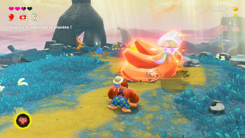 Un screenshot de Donkey Kong Bananza. Donkey Kong marche sur un chemin de terre et s'apprête à ramasser des BANANES. 