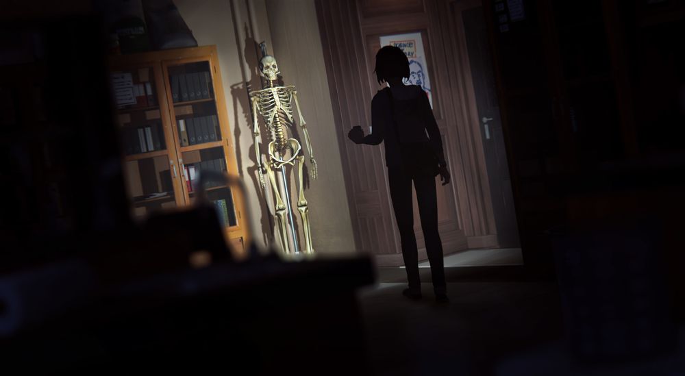 Un visuel du jeu Life is Strange. Dans la pénombre, l'héroïne éclaire de sa lampe de poche un squelette accroché dans le couloir d'un établissement scolaire.