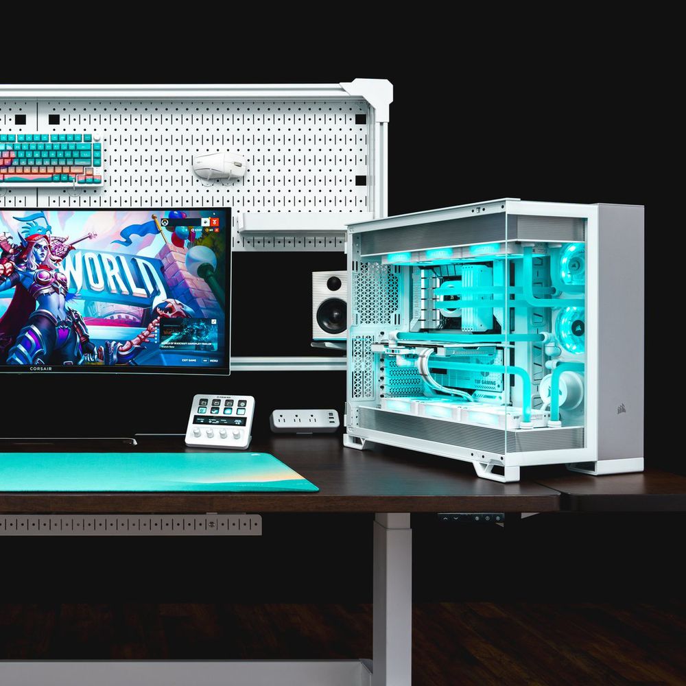The same 6500X Build ontop of a custom-painted CORSAIR Platform:6 Sit-Stand Desk with a white frame and pegboard and dark wood table. A monitor is mounted onto the desk's frame along with white speakers, an Elgato Stream Deck+, and a CORSAIR Custom Lab peripheral set.