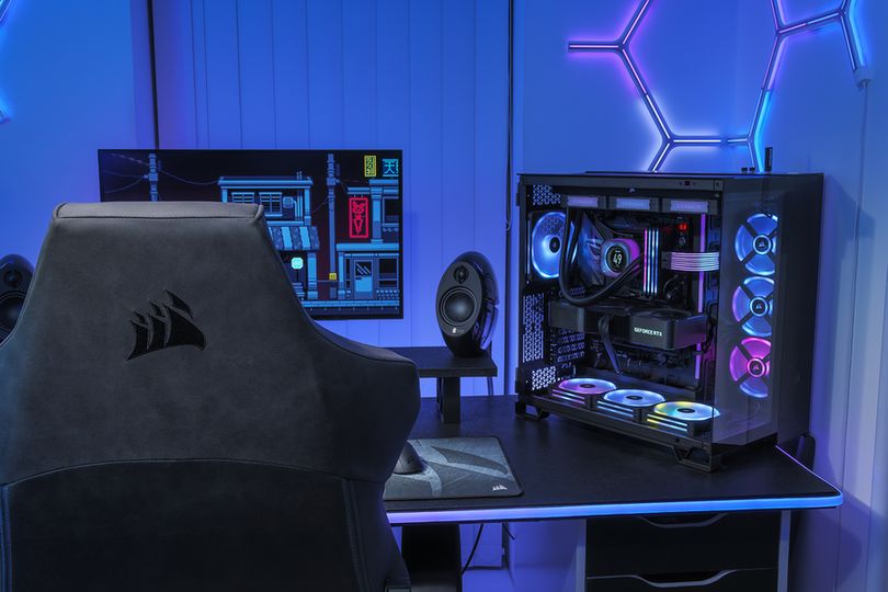 A photo of a CORSAIR TC500 LUXE gaming chair in front of a desk setup with a 6500X PC build.