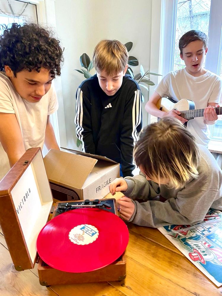 The band playing their new red vinyl album on a record player. 