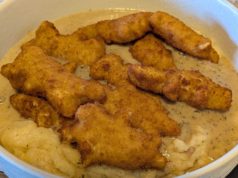 Mashed potatoes drowned in gravy with dinosaur shaped chicken nuggies