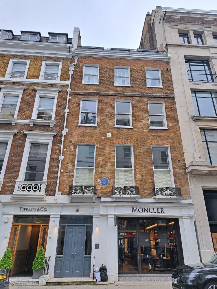Photograph [taken 2024] of 14 Albemarle Street, Mayfair, London W1S 4HL, showing an English Heritage blue plaque on the wall above the Moncler shopftont 