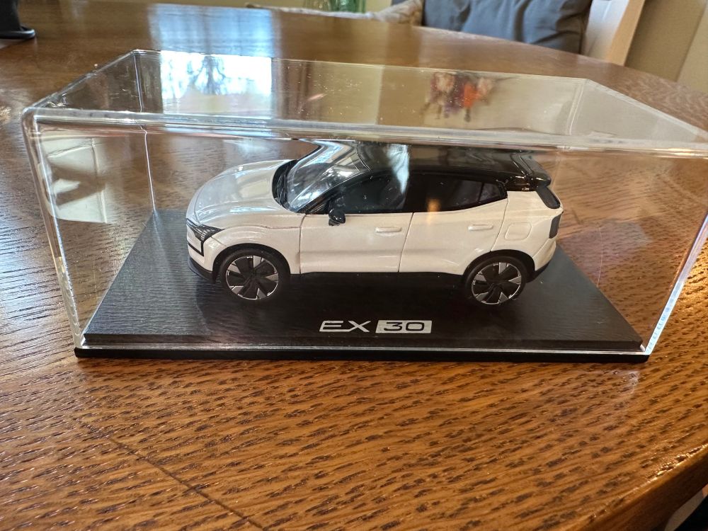 A scale model of the new Volvo EX30, presented in a plastic display case, sitting on a kitchen table.
