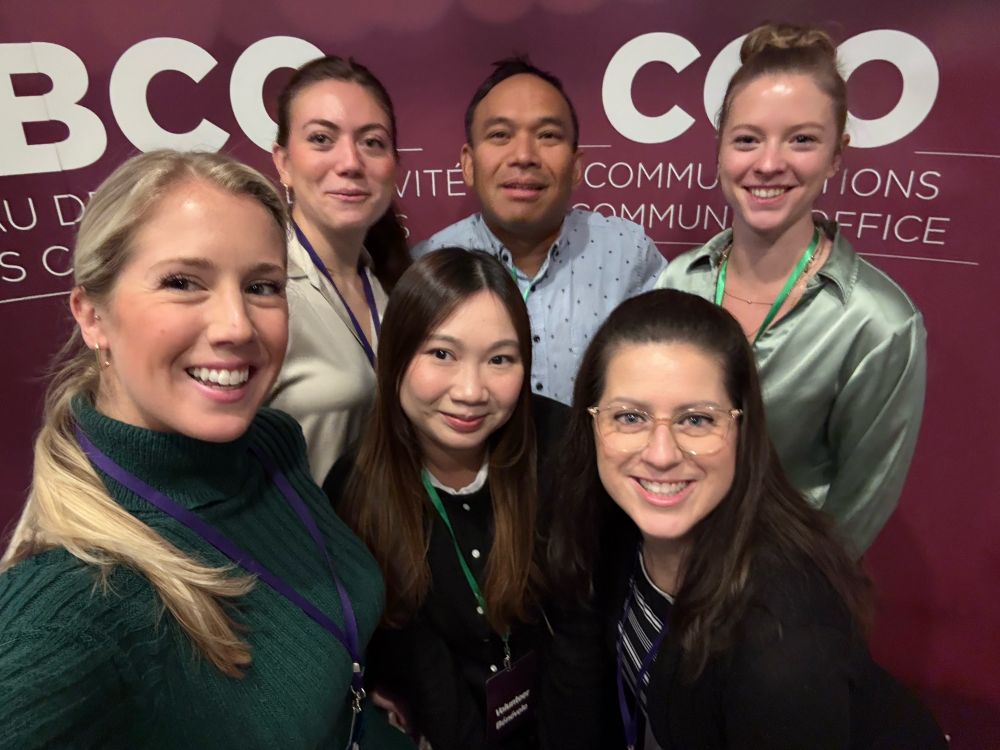 A group of six smiling individuals standing in front of a purple backdrop with white text that reads “BCO Communications Community Office.” The group includes three women in the front row and three individuals standing behind them. They appear to be at an event or conference, wearing name badges or lanyards.

Un groupe de six personnes souriantes debout devant un fond violet avec du texte blanc indiquant “BCO Communications Community Office.” Le groupe comprend trois femmes au premier rang et trois personnes debout derrière elles. Elles semblent être à un événement ou une conférence, portant des badges ou des cordons.
