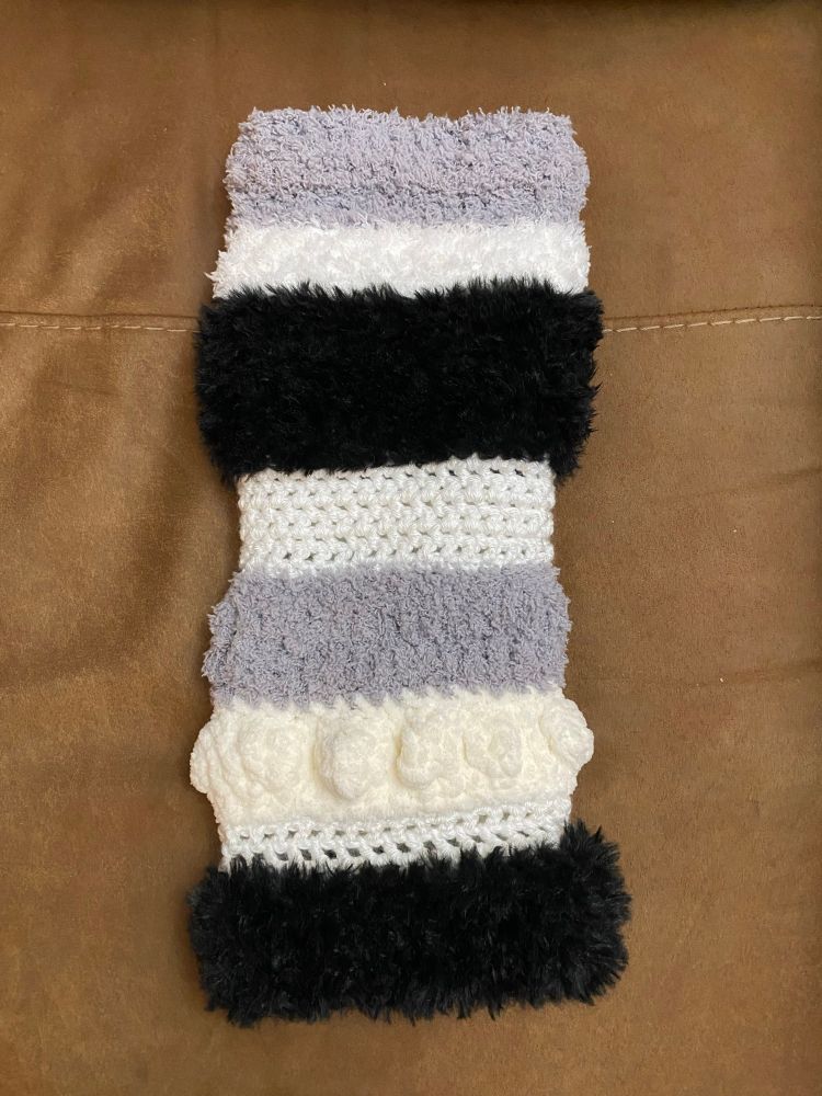 Crocheted twiddle muff in black, gray, and white stripes of yarn with different textures and stitches, meant to be a sensory experience