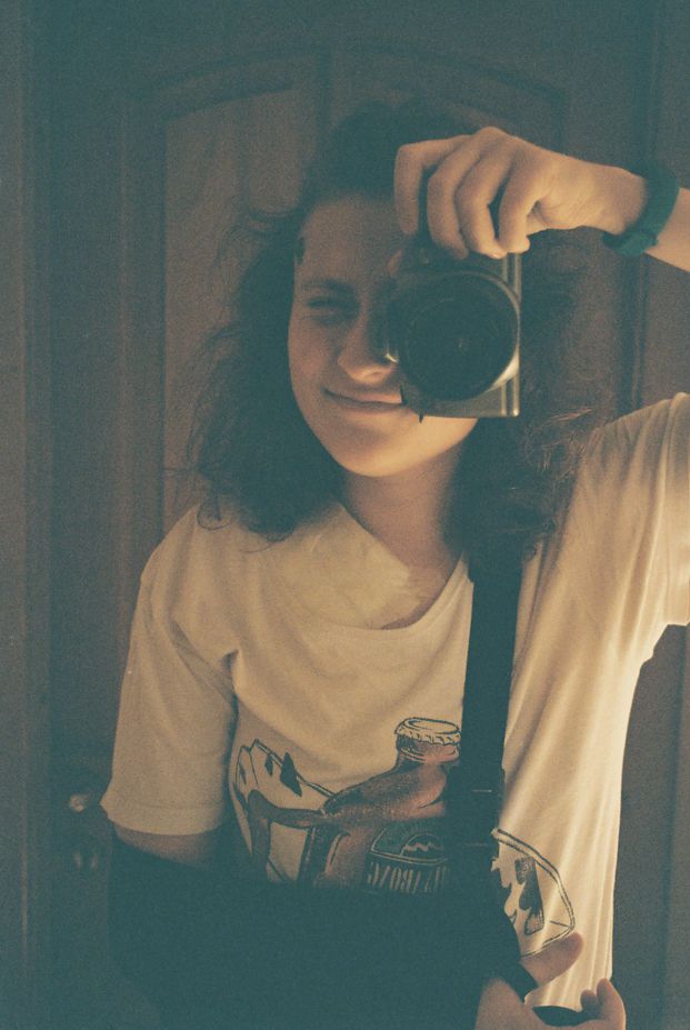 a person taking a picture of themself in a mirror with a film camera