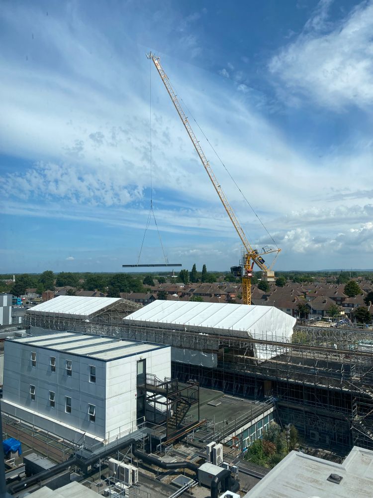 Crane lowering a girder into position, as part of new roof for the Ventilation Inpatient Centre at Aintree Hospital