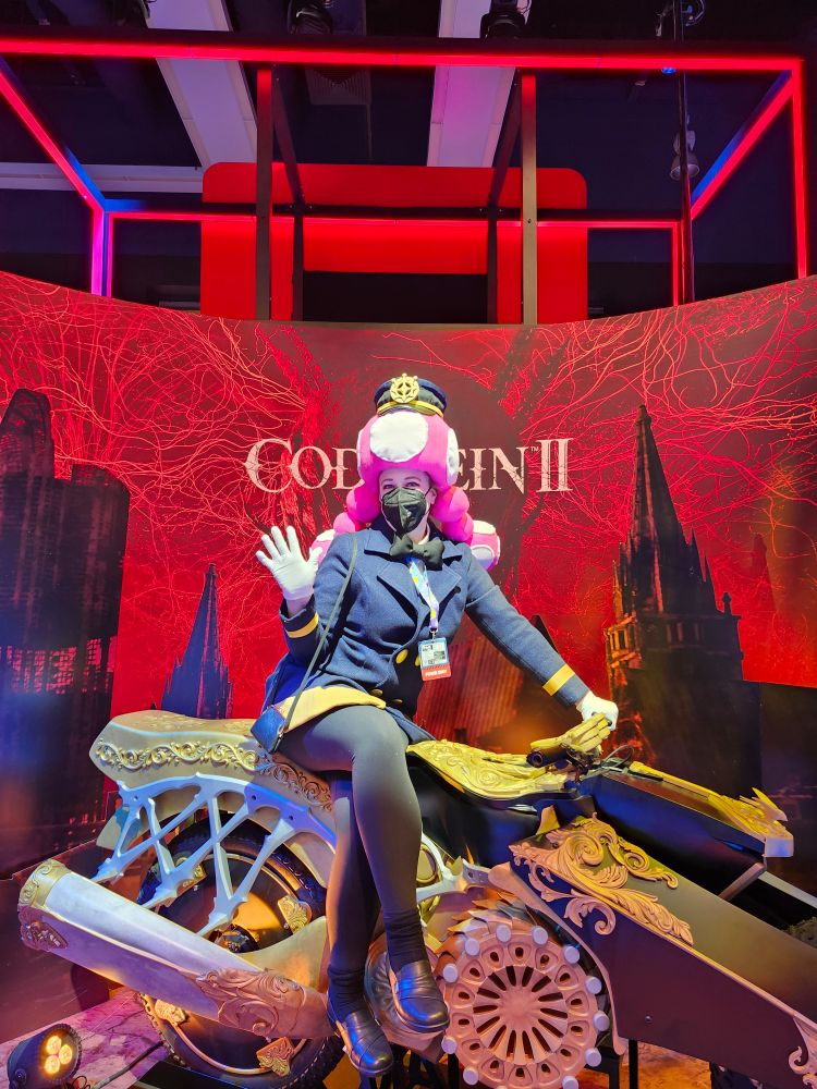 A woman dressed as a train conductor toadette on a really cool gold motorcycle