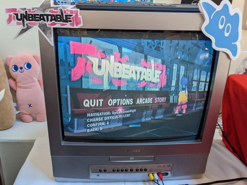 Title screen for the Unbeatable game on a silver Toshiba CRT TV. 
