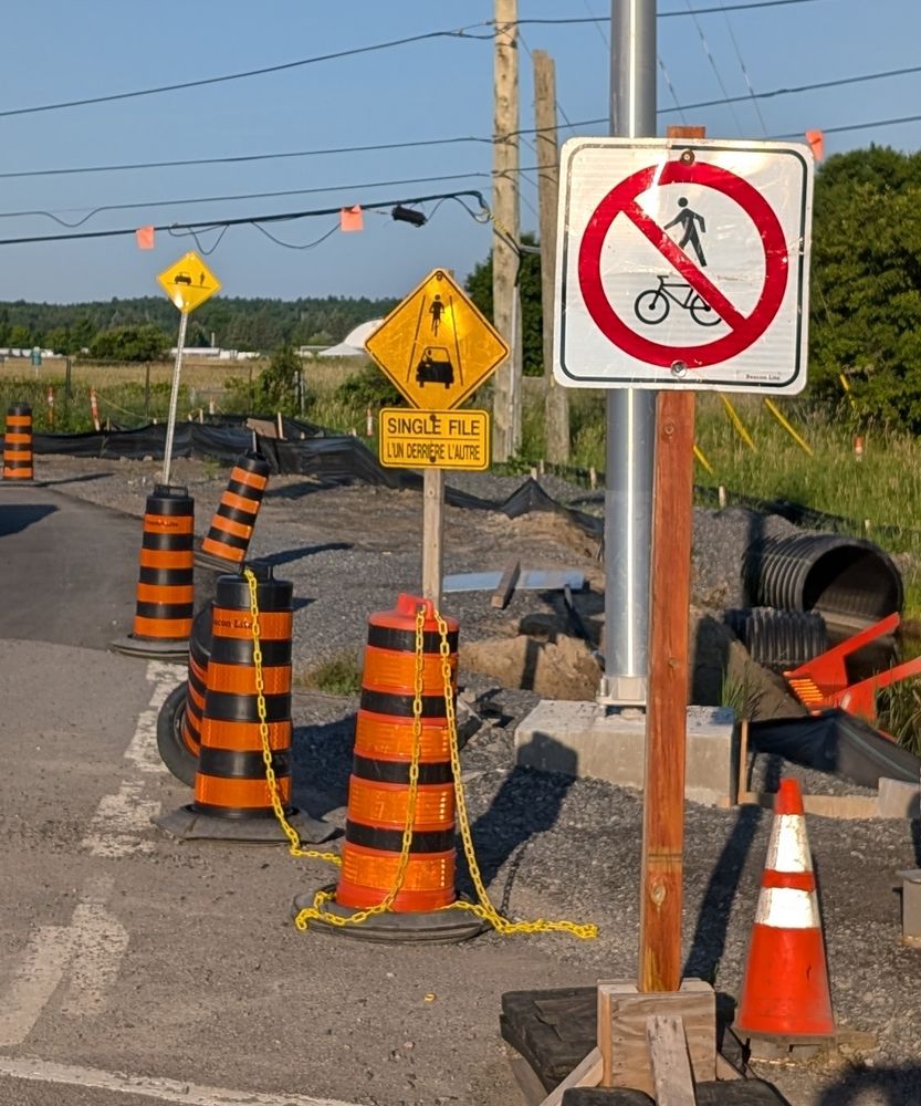 A series of 3 road signs, foremost "no bikes or pedestrians", behind that "single file" and then "share the road". Taken at the intersection of Moodie Drive and Corkstown Road.