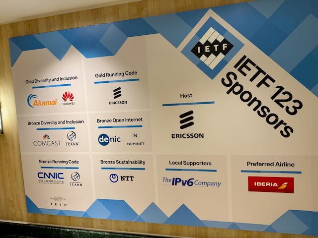 Sponsor board for the IETF 123 Madrid meeting displaying logos of various sponsors, including Akamai, Comcast, DENIC, Ericsson, NTT, and IBERIA, categorized under titles like Gold Diversity and Inclusion, Gold Running Code, and more.