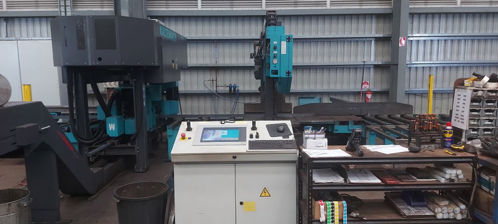 A Kaltenbach KDB 1015(L, 3-axis CNC machine)/KBS 1010(R, CNC bandsaw) beamline machine, with console at front