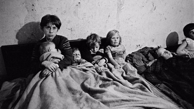Manchester, 1960s. Four children and mother in bed in slum housing.