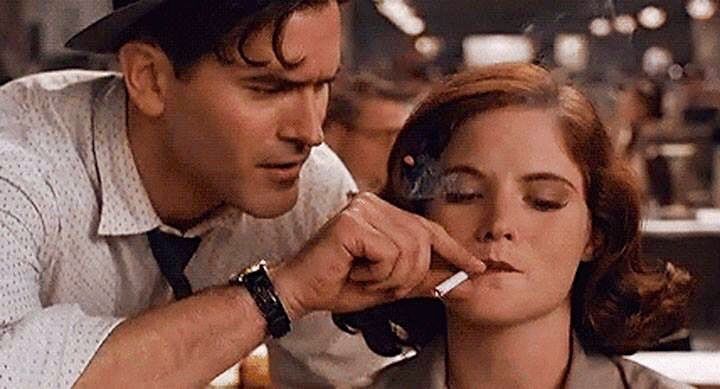 Bruce Campbell demurly holding Jenifer Jason lee's cigarette to her mouth while she types a Pulitzer winning article 
