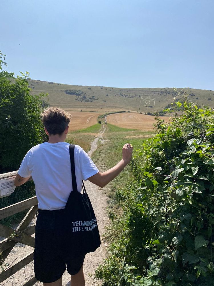 Woman opens gate on footpath British countryside.