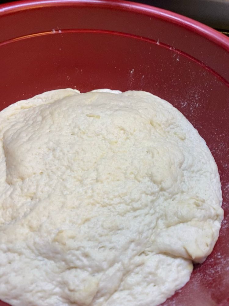 Focaccia dough after the first rise in a red bowl.