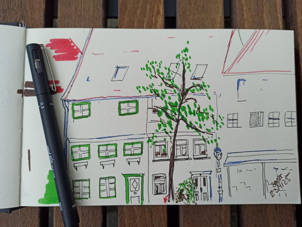 Skizze mit Fineliner und Pitt Dual Markers. Zwei Häuser und ein Baum an einem Platz
