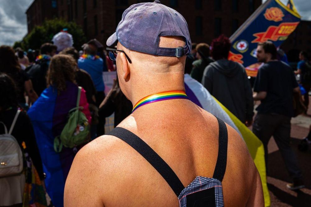 A man wearing a rainbow pride ribbon around his neck, at Liverpool Pride.