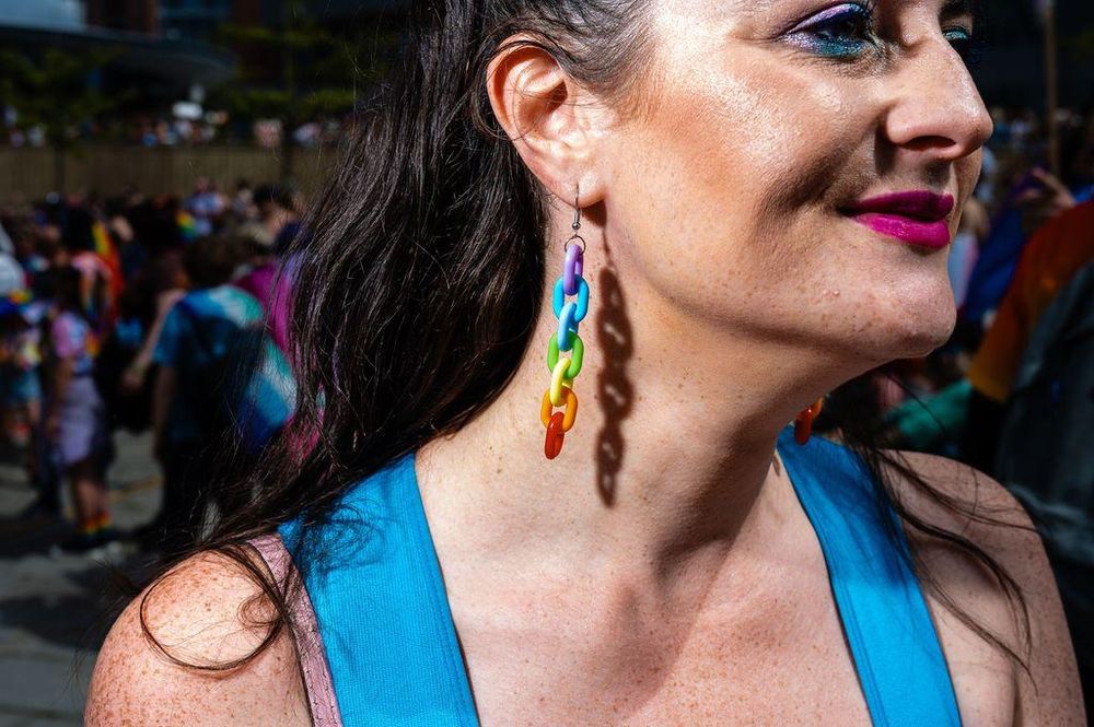 A woman at Liverpool Pride wearing rainbow earrings and makeup.