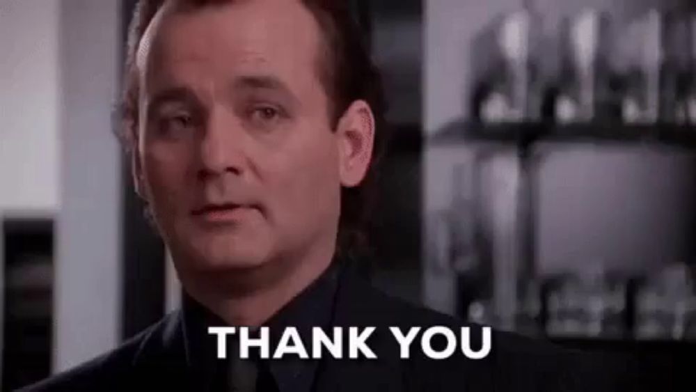 a man in a suit and tie is giving a thank you sign .