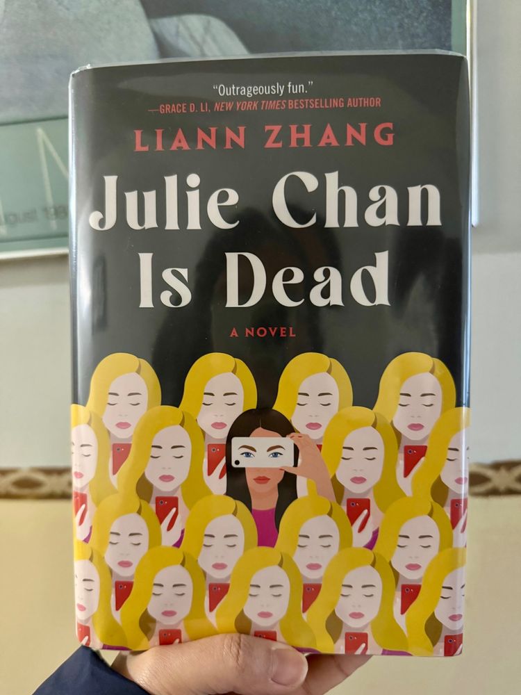 Hardcover of Julie Chan Is Dead by Liann Zhang featuring identical blond women with one black-haired woman in the center with a phone over her eyes