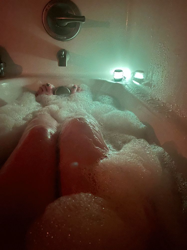 A gif with four frames, each in low light. They each show my thighs and knees from where I’m sitting in a bubble bath. The first two frames are in low white light, the second is in low red light, and the third is in low blue light.  