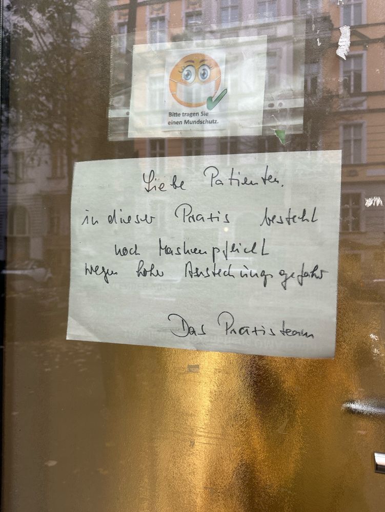 Eingangstür einer Hausarztpraxis mit Maskenpflichtschild