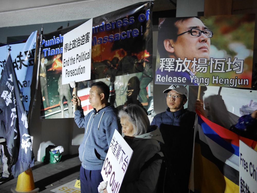 People holding signs for an end to political persecution in China